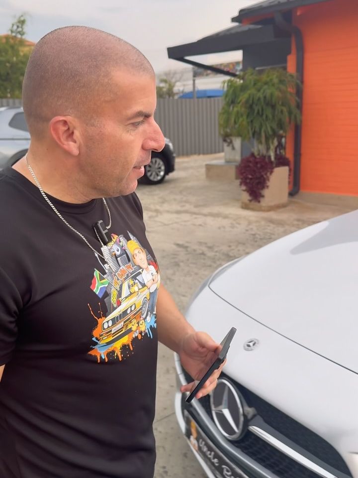 Uncle Bobby on his phone next to a Mercedes